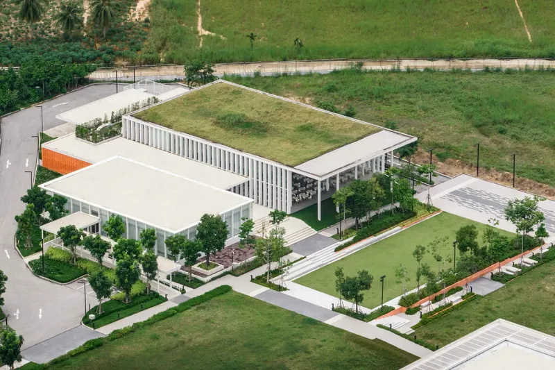 Aerial perspective showing the grass-covered roof and white vertical louvered facade with landscaped surroundings
