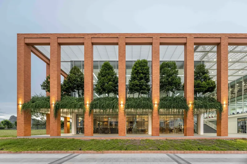 Timber frame facade with planted green terrace beneath vertical louvers illuminated at twilight