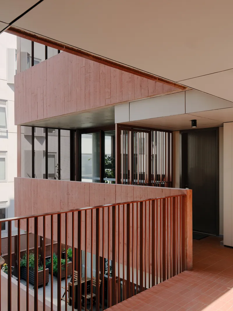 Multi-level circulation space with pink timber slat balustrades and planted beds at ground level