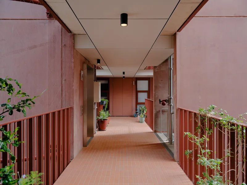 Corridor with pink vertical slat railings and planters on both sides under a recessed panel ceiling