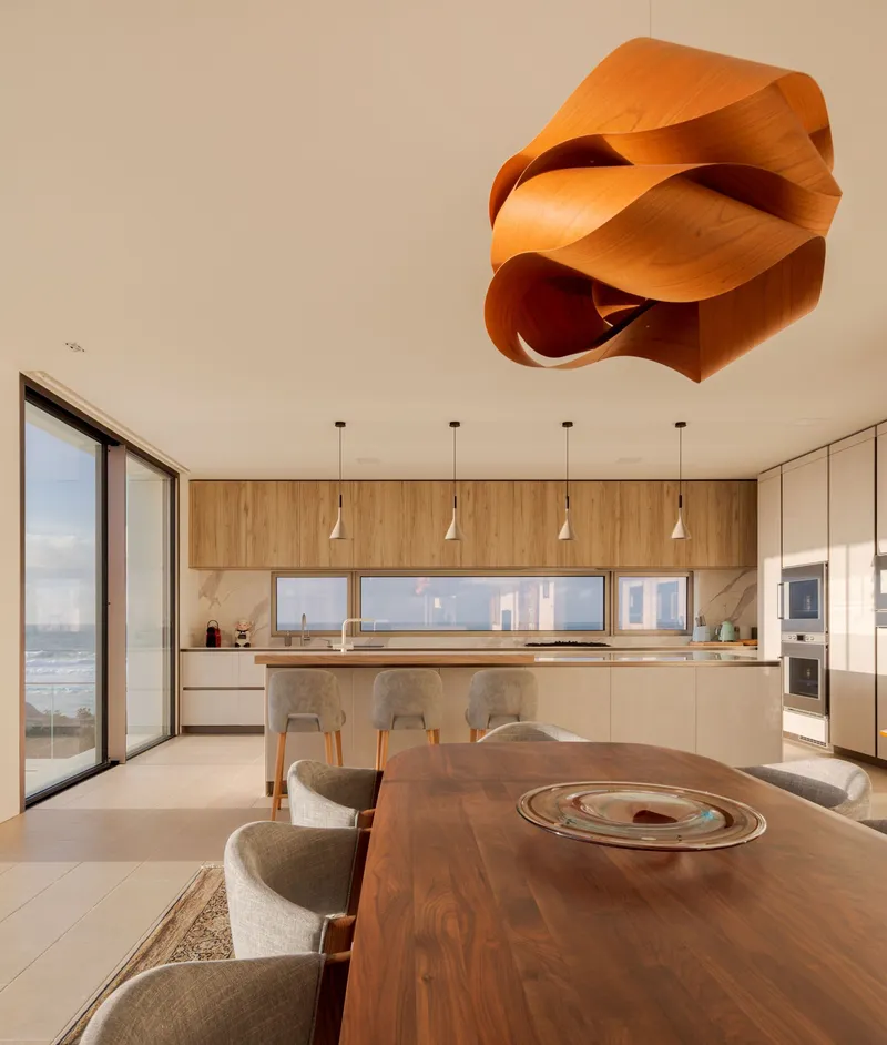 Open kitchen and dining area with sculptural wood pendant light and ocean views
