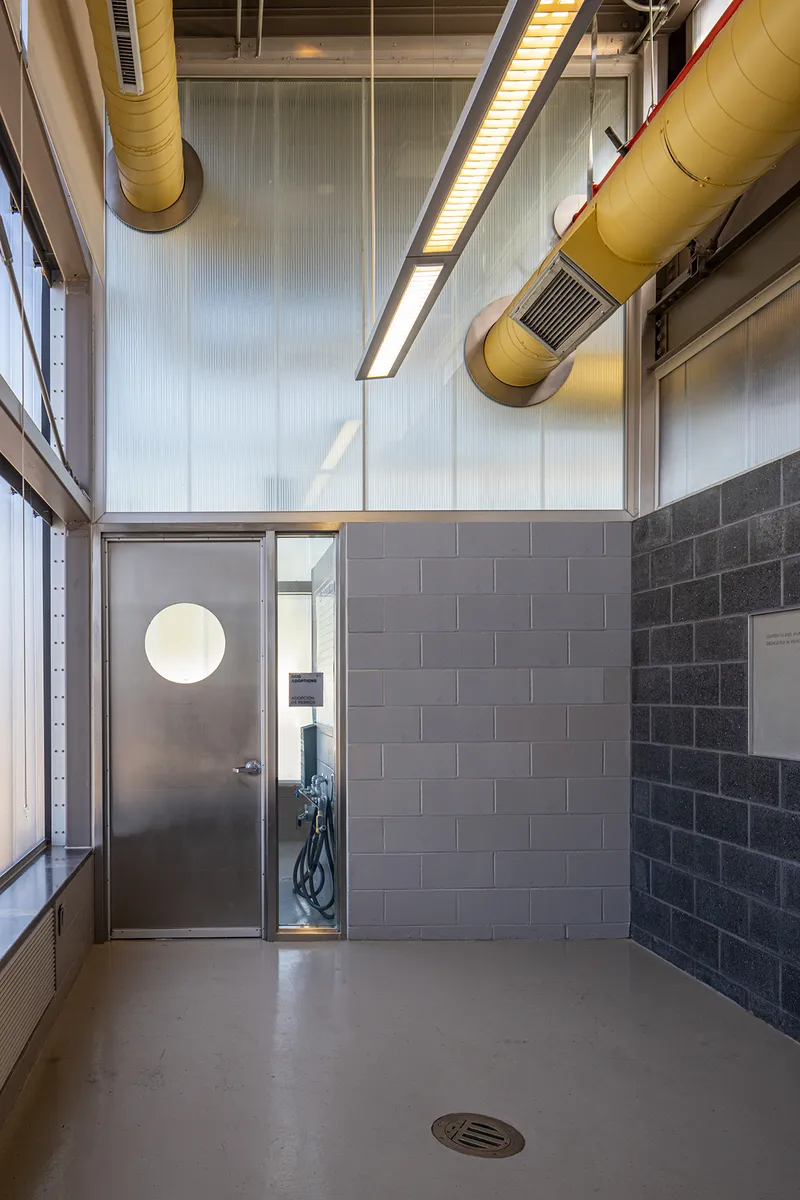 Interior corridor with exposed yellow ductwork, concrete masonry walls and circular porthole door