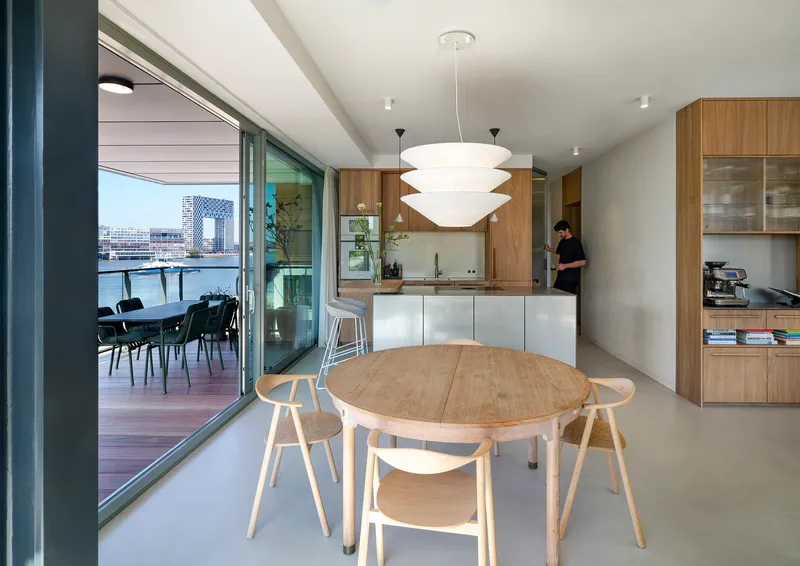 Open-plan kitchen and dining area with timber cabinetry and sliding doors to the balcony