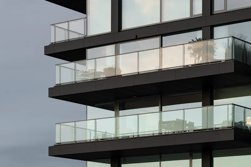 Stacked cantilevered balconies with glass railings and full-height glazing at twilight