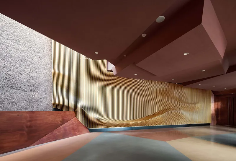 Interior lobby with vertical timber screen wall and angular red-brown ceiling planes
