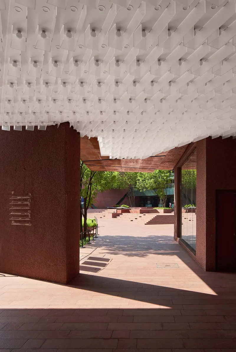 Covered passageway with timber soffit and white modular ceiling panel grid in bright daylight