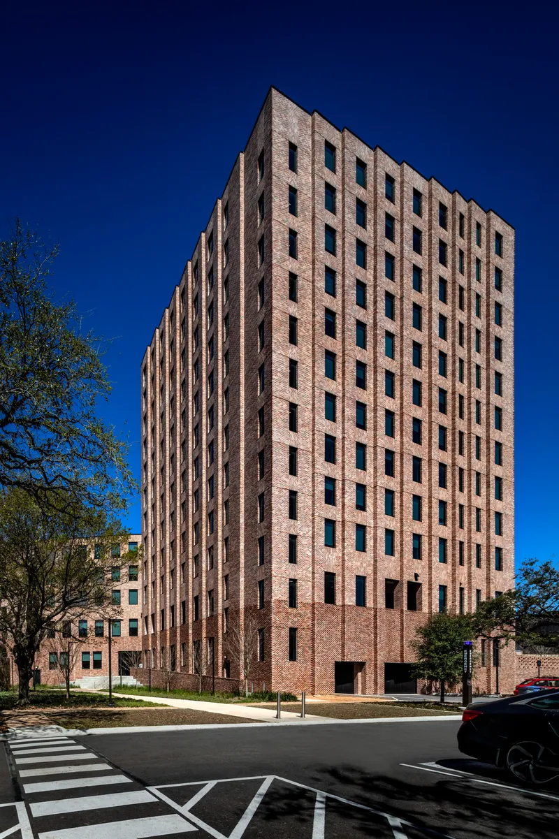Brick tower facade with vertical window pattern against a deep blue sky