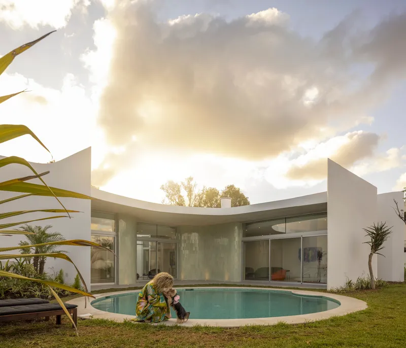 Circular pool in a grass courtyard with a person and dog at sunset
