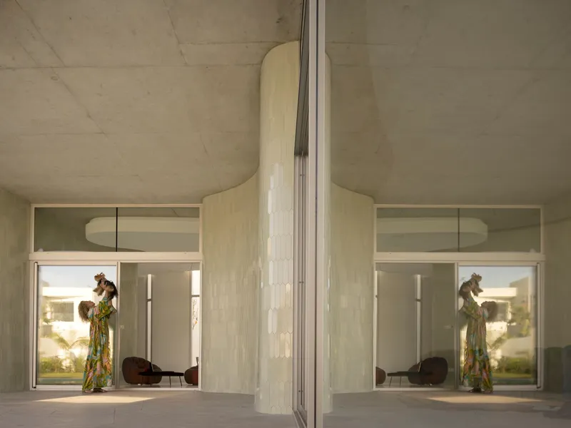 Glass wall reflection showing a person in the interior with exposed concrete ceiling