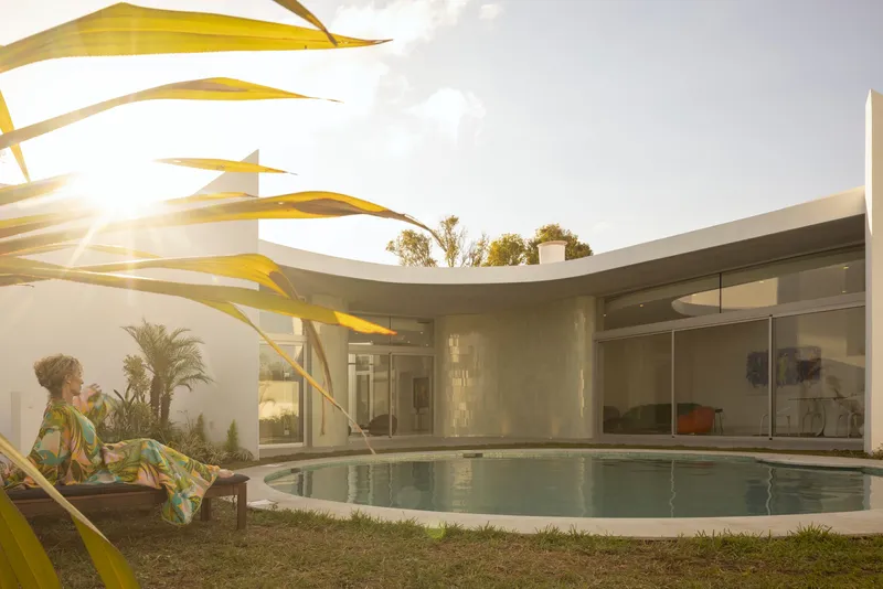 Courtyard pool framed by palm fronds with a person seated in late afternoon sun