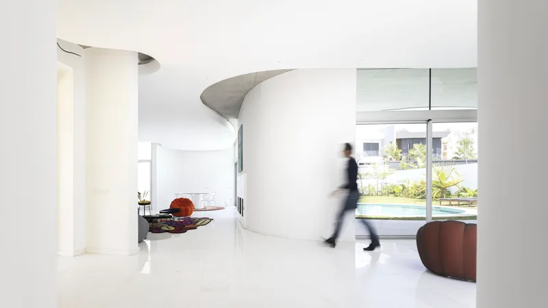 Open interior with white polished floors and a figure in motion passing a curved partition wall