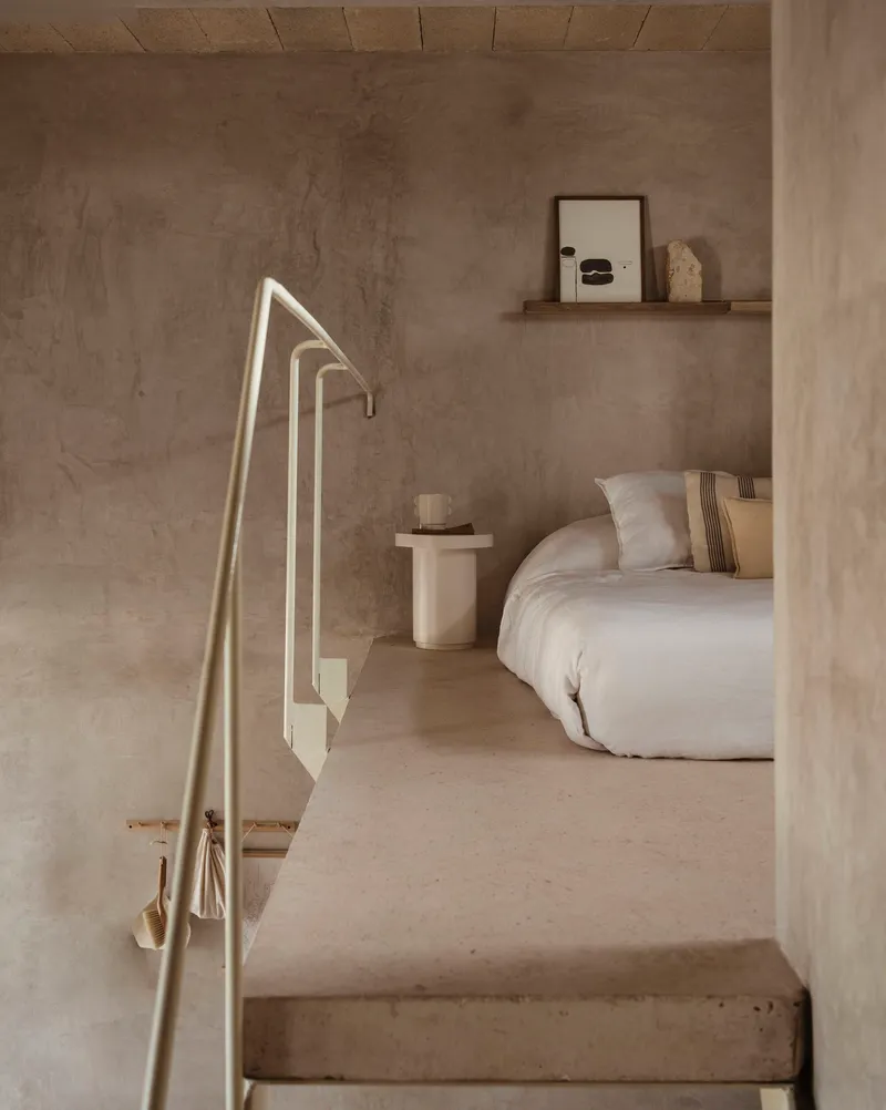 Bedroom entry framed by concrete columns and metal handrail with soft natural light
