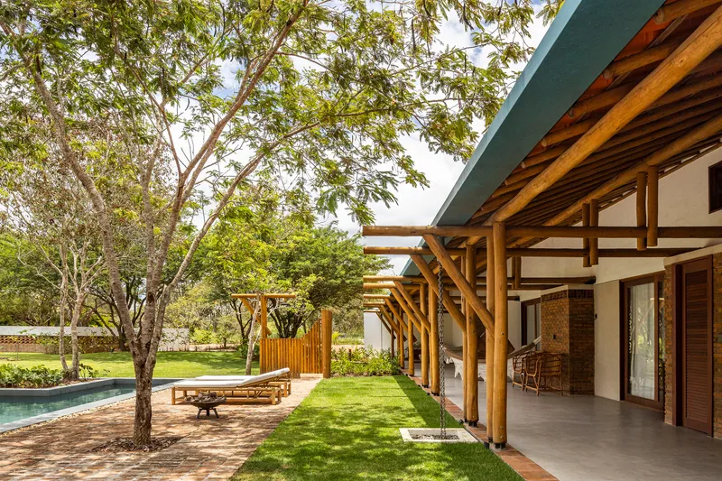 Covered porch with exposed timber rafters and beams overlooking a lawn shaded by mature trees