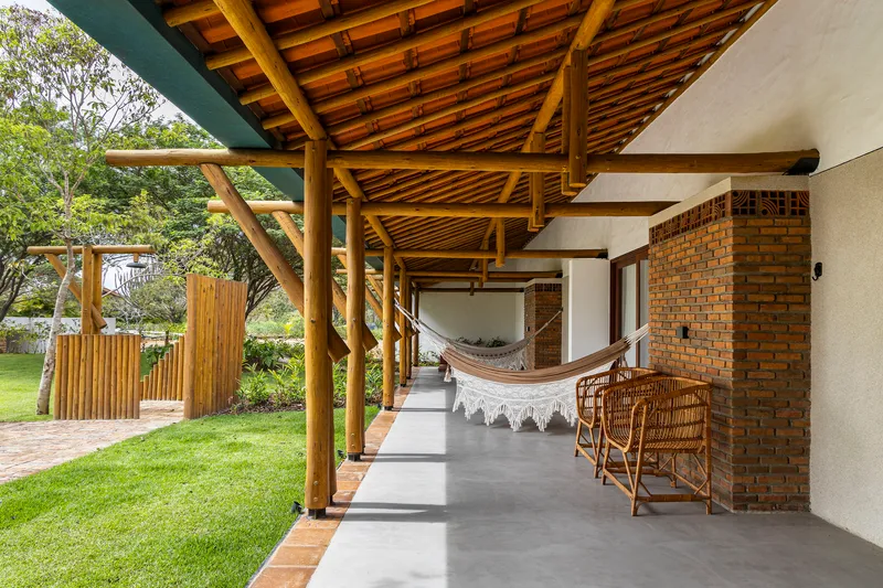 Covered terrace with exposed timber ceiling, concrete floor and hammock looking toward the lawn