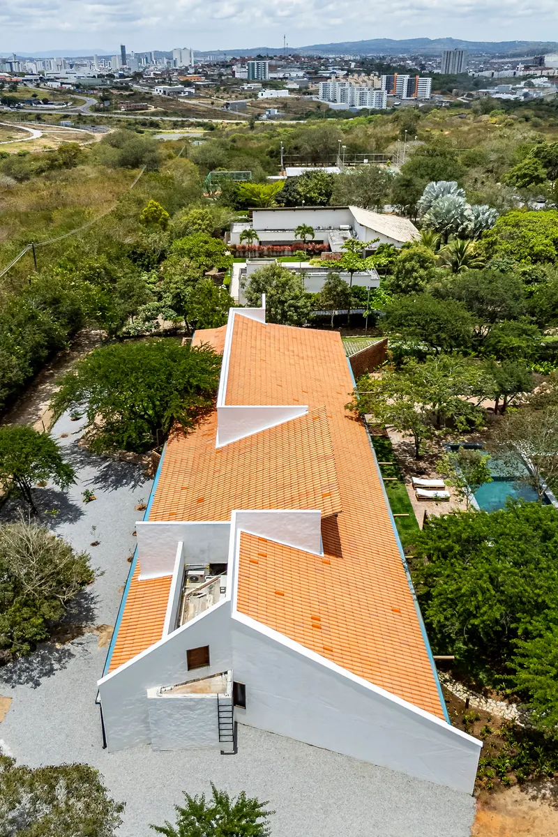 Drone view showing the segmented orange tile roof extending linearly through dense vegetation