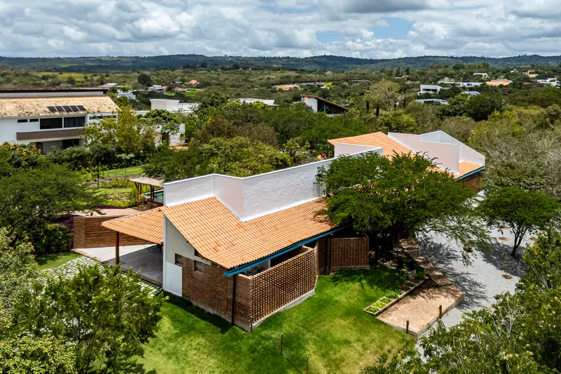 Aerial perspective of interlocking orange tile roof volumes with perforated brick screen and courtyard