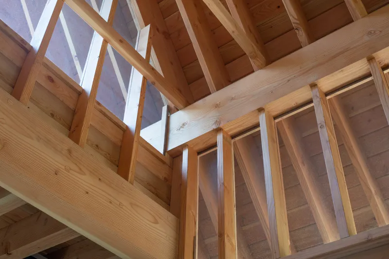 Corner detail of timber ceiling joists meeting clerestory glazing in natural light