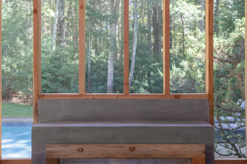 Built-in concrete bench with timber frame window overlooking forest