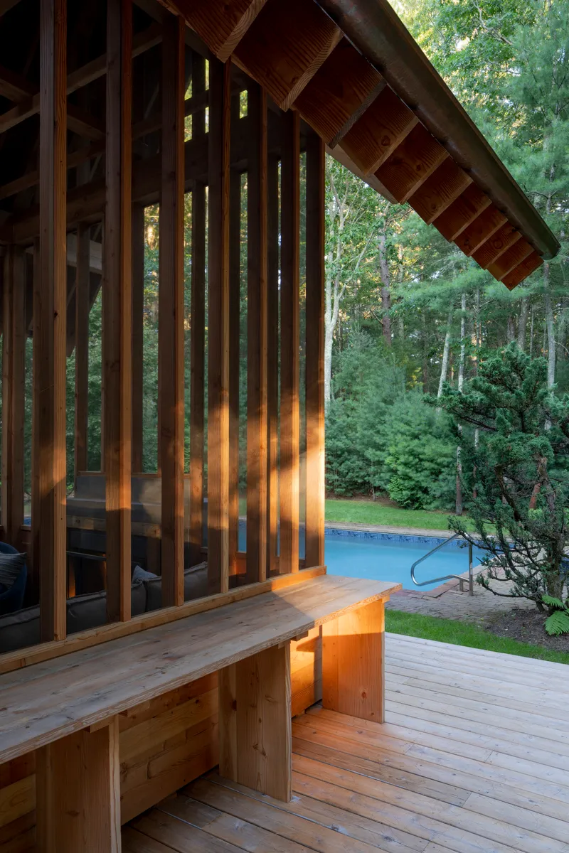 Corner detail of the vertical timber screen with built-in bench at dusk beside the pool