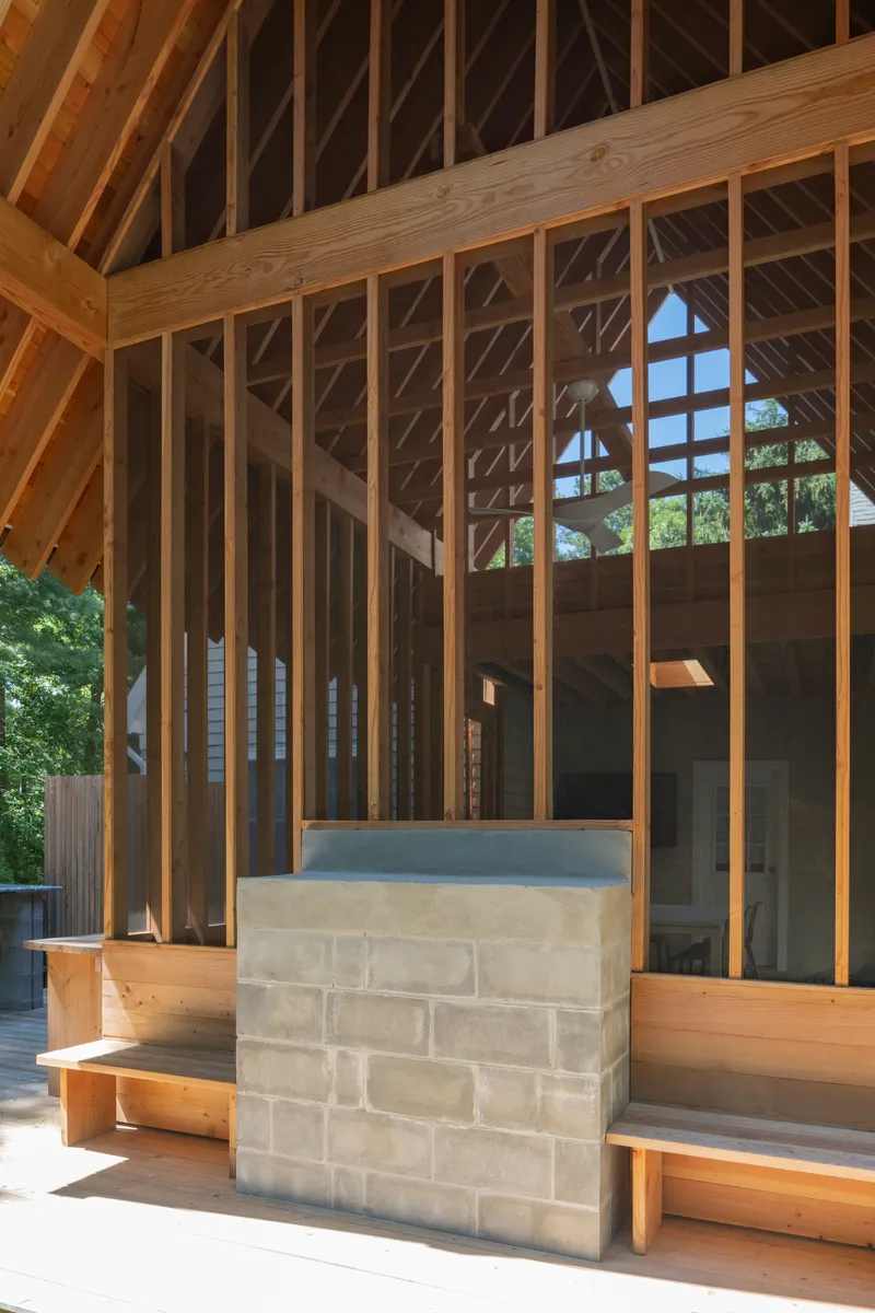 Detail of concrete block bench flanked by timber posts beneath the gabled roof structure