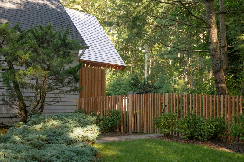 Timber slatted fence enclosing a garden path with planted beds in late afternoon light