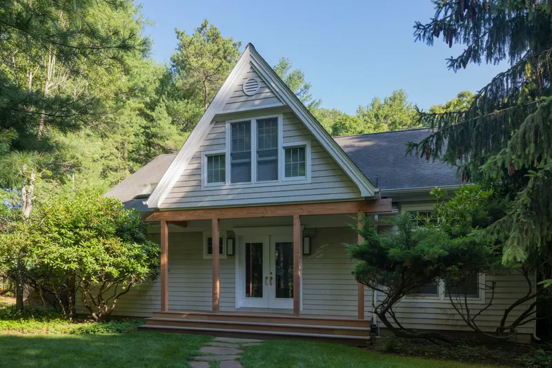 Front porch with timber columns and triangular gable vent beneath a clear summer sky