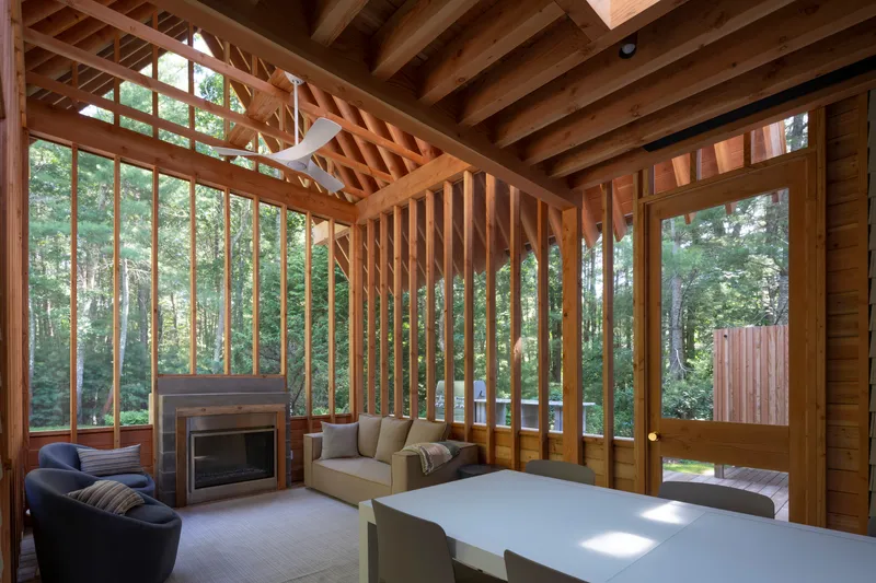 Interior with exposed timber rafters and vertical screen framing a fireplace and seating area