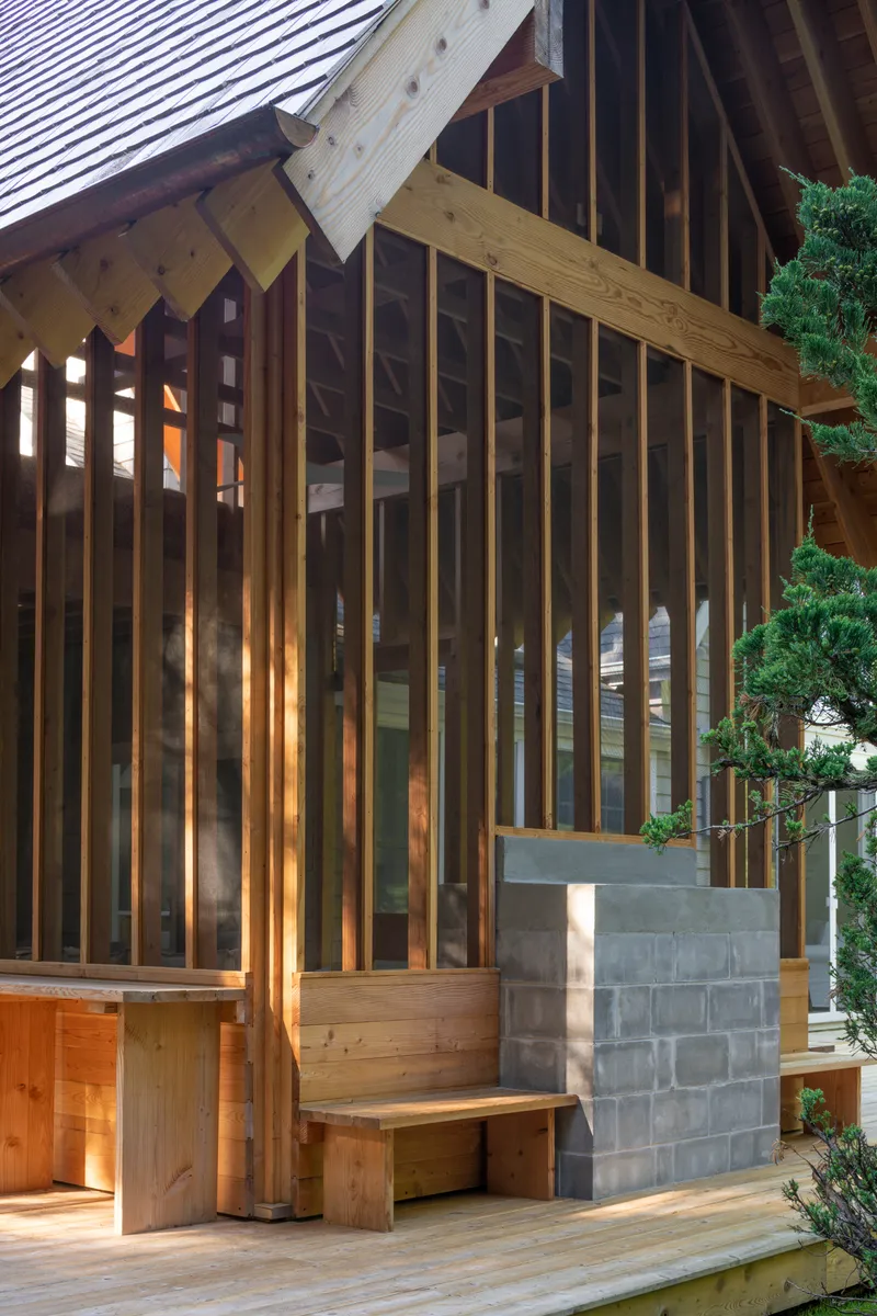 Timber screen facade with vertical slats and concrete block base at dusk