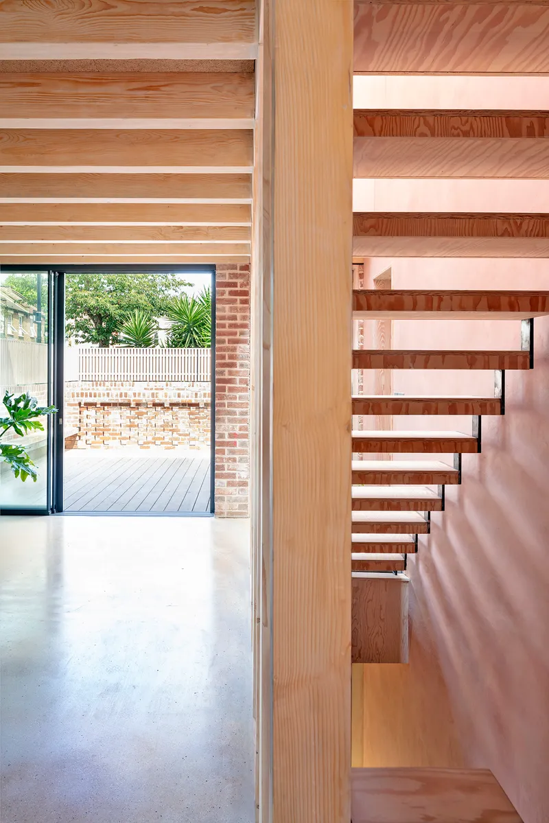 Timber open-tread staircase beside a glazed door leading to a timber-decked courtyard
