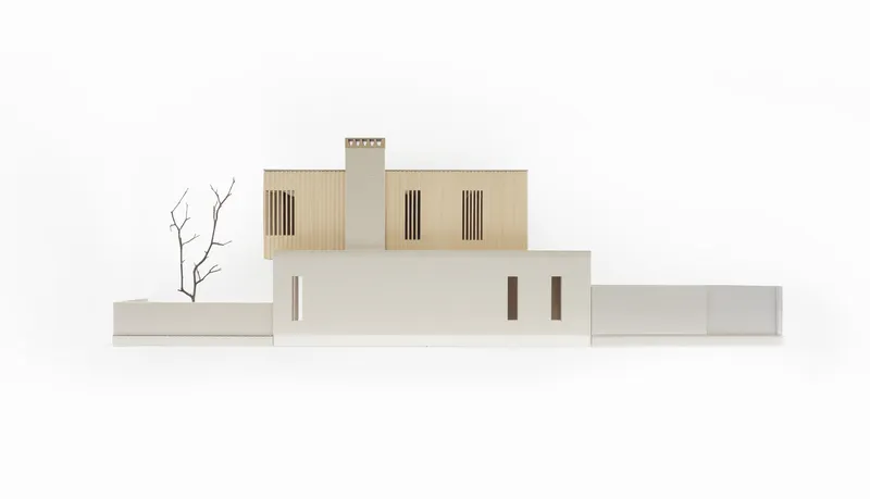 Physical model of the front elevation showing stacked volumes with vertical slatted openings and miniature tree