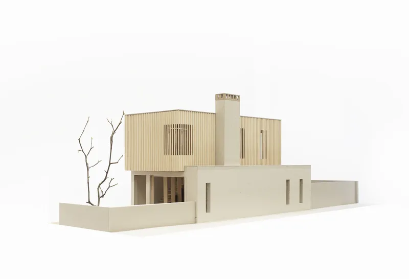 Physical model from corner view displaying stacked massing with timber cladding and courtyard walls