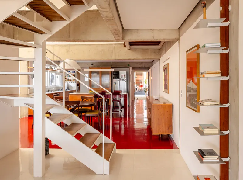 Mezzanine level view showing white steel staircase, red flooring and exposed concrete ceiling with timber insets