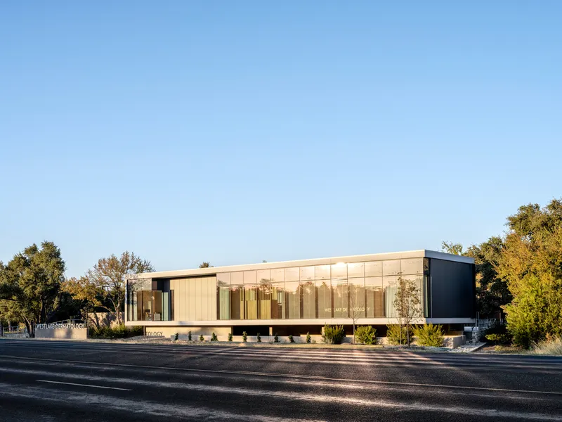 Street view of the long glass facade with vertical fins between dark side volumes