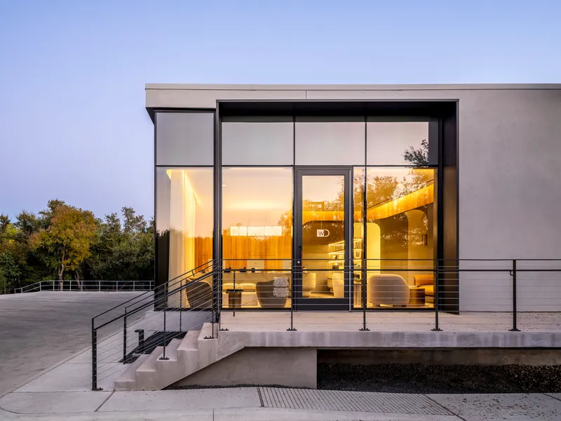 Illuminated glazed entry at twilight with view through to timber-lined interior