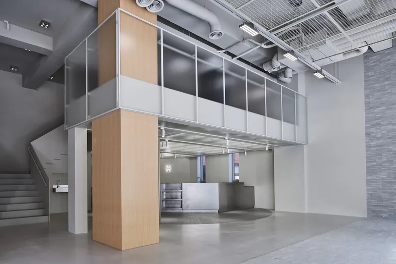 Two-story pavilion with wood and metal panels suspended over the polished concrete lobby floor