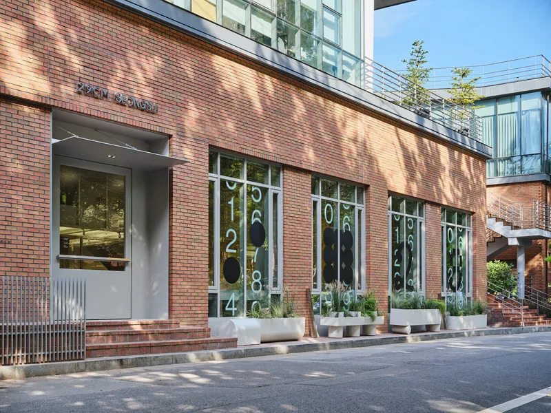 Entrance facade in red brick with numerals on glazed storefronts and planters below
