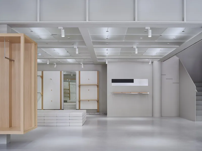 Interior view showing light wood framed display niches, white shelving, and cofferred ceiling with pendant lighting