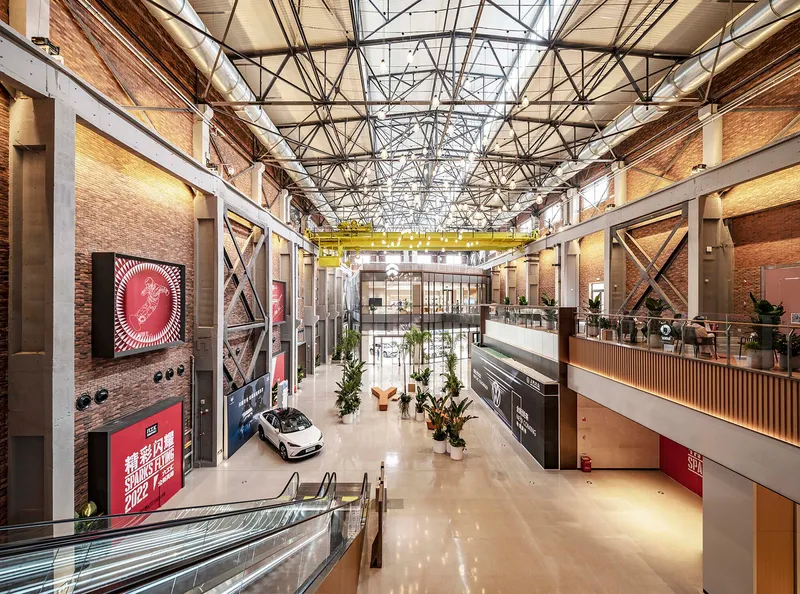Interior hall with exposed steel trusses, brick walls, mezzanine levels and a display car on polished floor