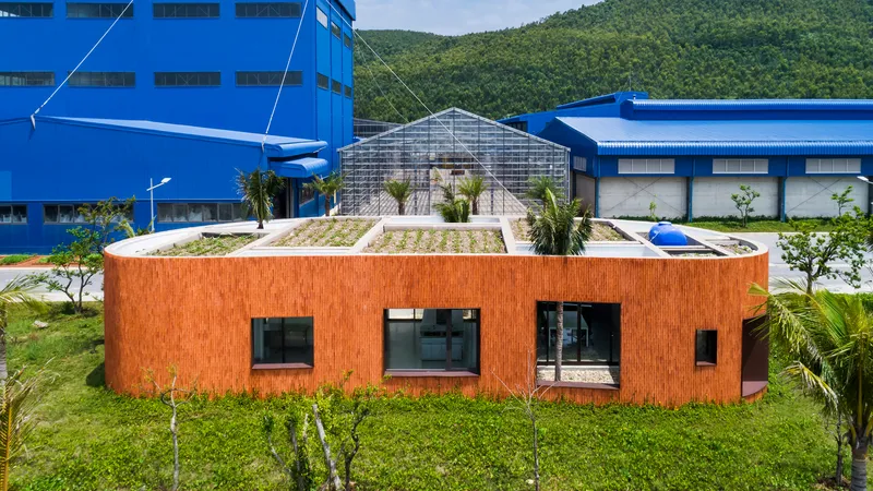 Planted green roof atop the curved brick structure with blue industrial buildings behind