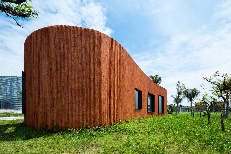Vertical brick cladding wrapping the curved facade with three rectangular window openings
