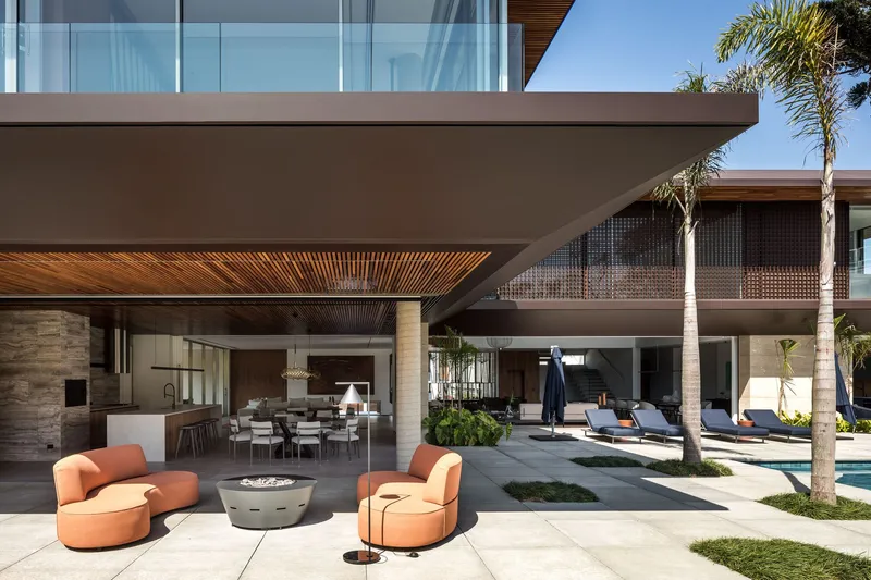 Covered outdoor terrace with timber slatted ceiling and stone columns opening to the poolside lounge area