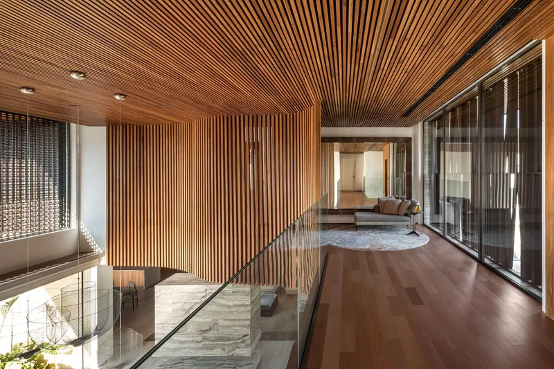 Upper-level walkway with timber slat ceiling and walls overlooking the living space below