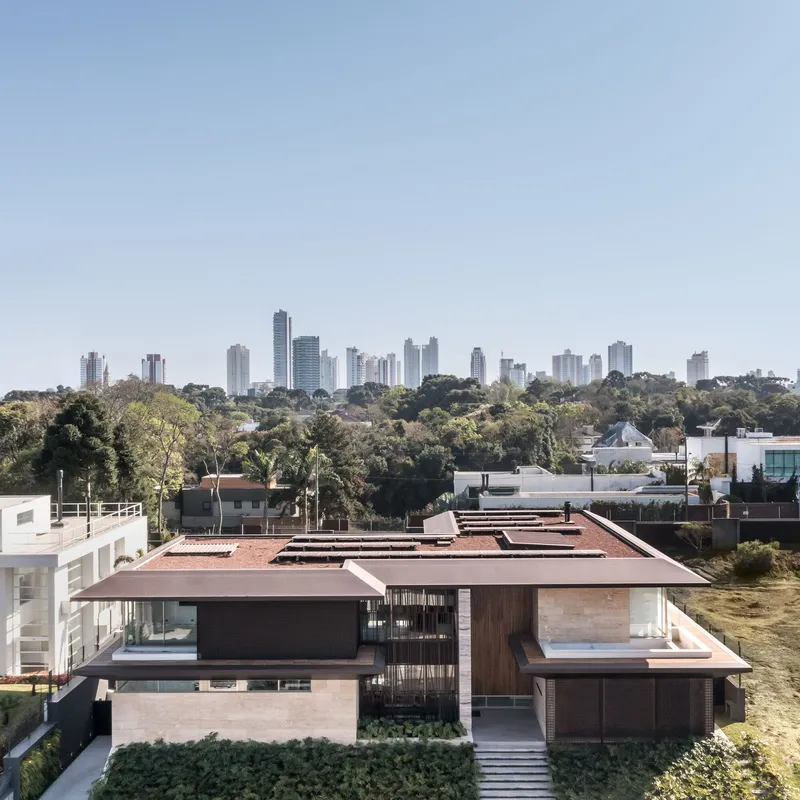 Elevated view of the stepped terracotta roof volumes with distant skyline visible beyond treetops