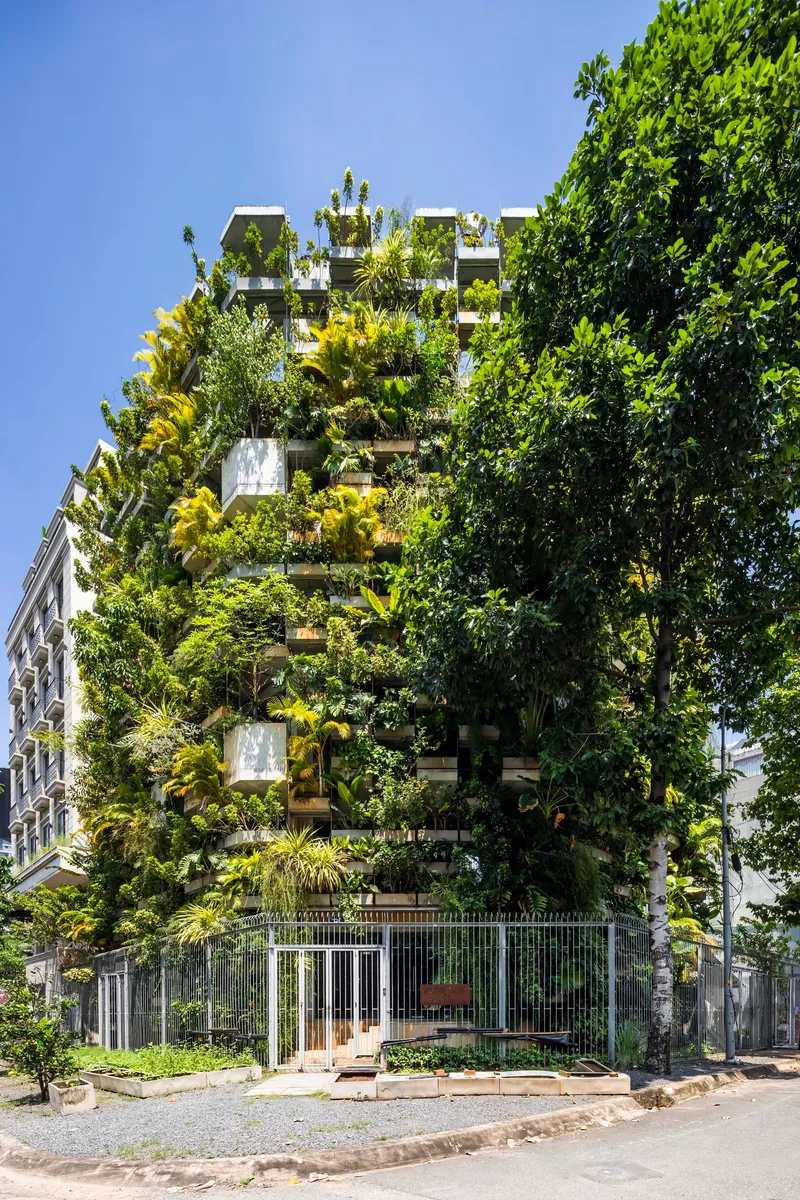 Street elevation showing the planted tower behind a low perimeter fence and entry gate