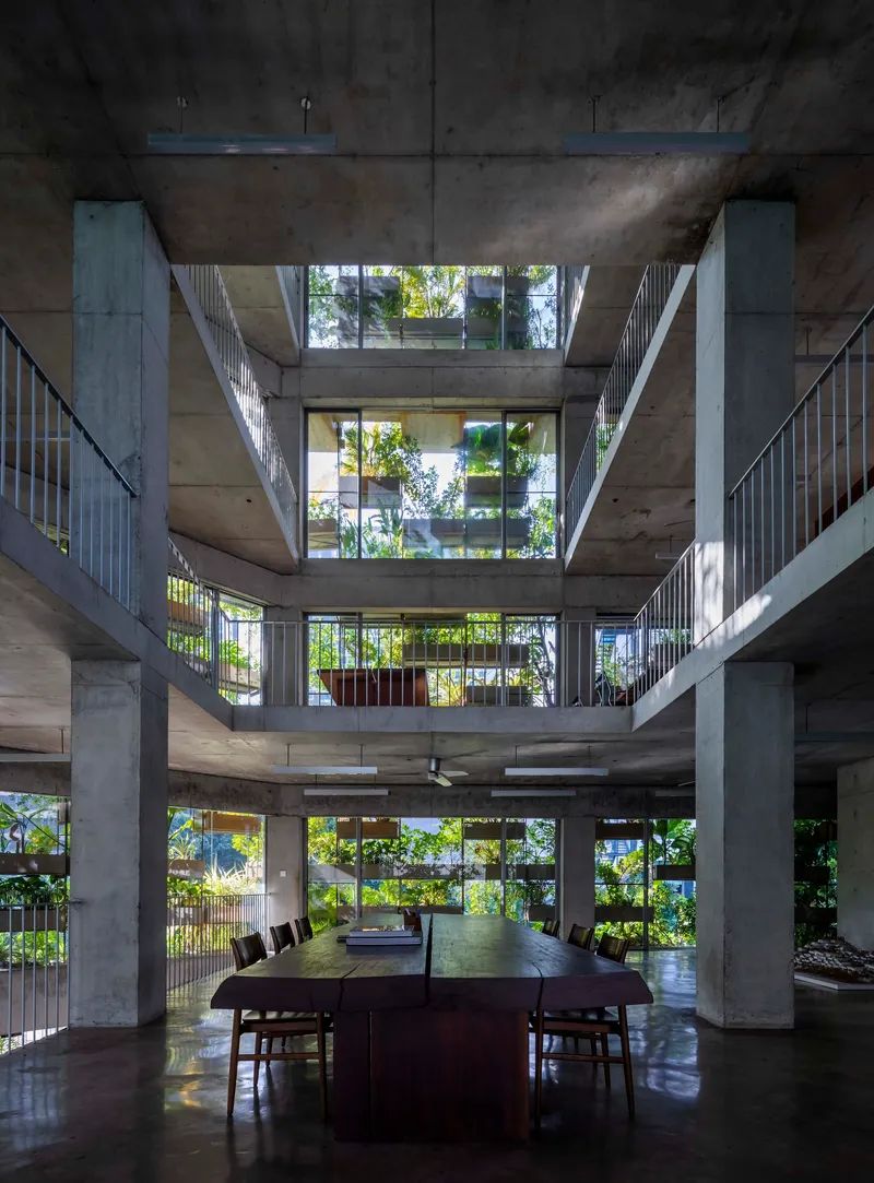 Central void looking up through stacked concrete slabs and metal railings with planted terraces above