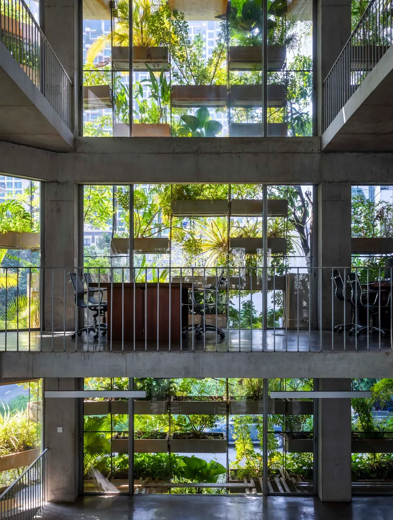 Vertical view through the atrium showing three levels of planted concrete slabs and metal balustrades