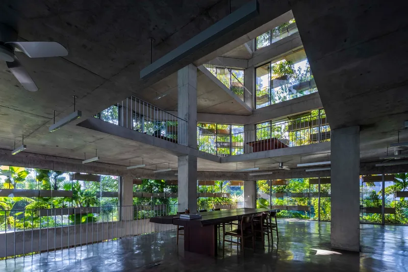 Open-plan interior with concrete columns and slabs framing planted balconies beyond full-height glazing