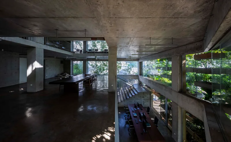 Open kitchen and dining area overlooking lower level seating with filtered sunlight through planted slabs