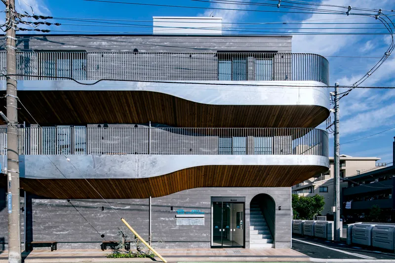 Front elevation showing the stacked cantilevered terraces with wood soffits and corrugated metal screening above stone base