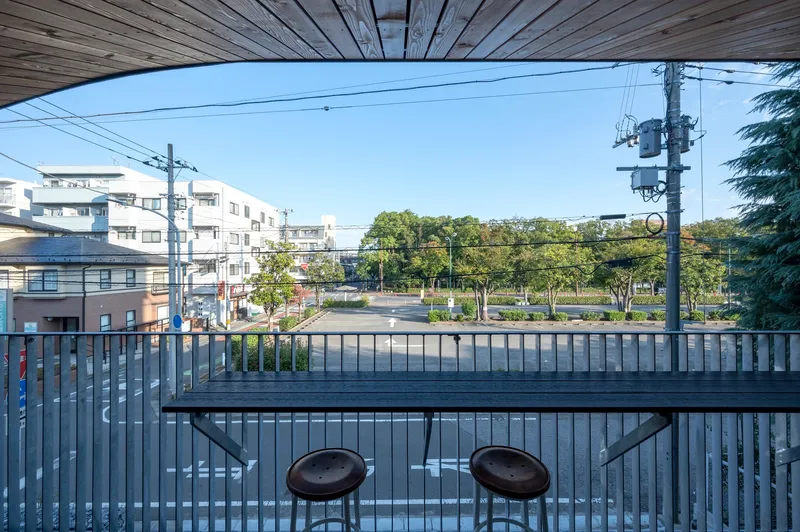 Upper level balcony with wood ceiling, metal railing and counter overlooking residential rooftops and trees